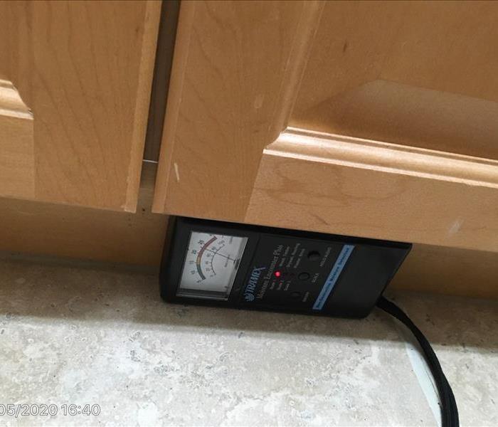 Moisture meter is being used to check the affected kitchen cabinets